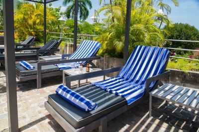 Striped towels draped on lounge chairs by a side table with drinks, surrounded by palms at Hotel Montana Haiti