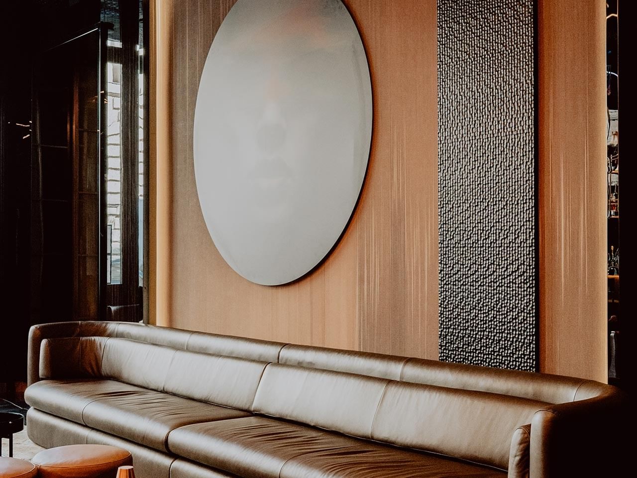 Modern hotel lobby with leather sofa, round mirror, and textured wall panels at Titanic Gendarmenmarkt Berlin