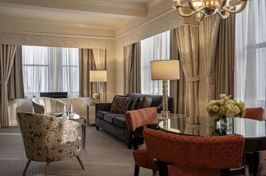 Elegant hotel suite with couch, chairs, and dining table at Warwick New York.