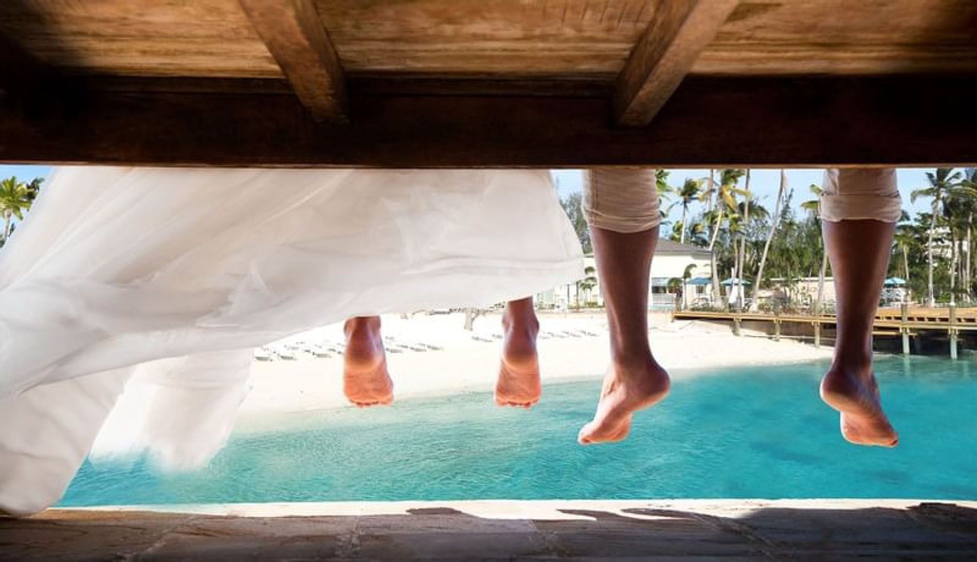 Guest feet by a pier under a wooden bench surrounding turquoise ocean water at Warwick Paradise Island Bahamas