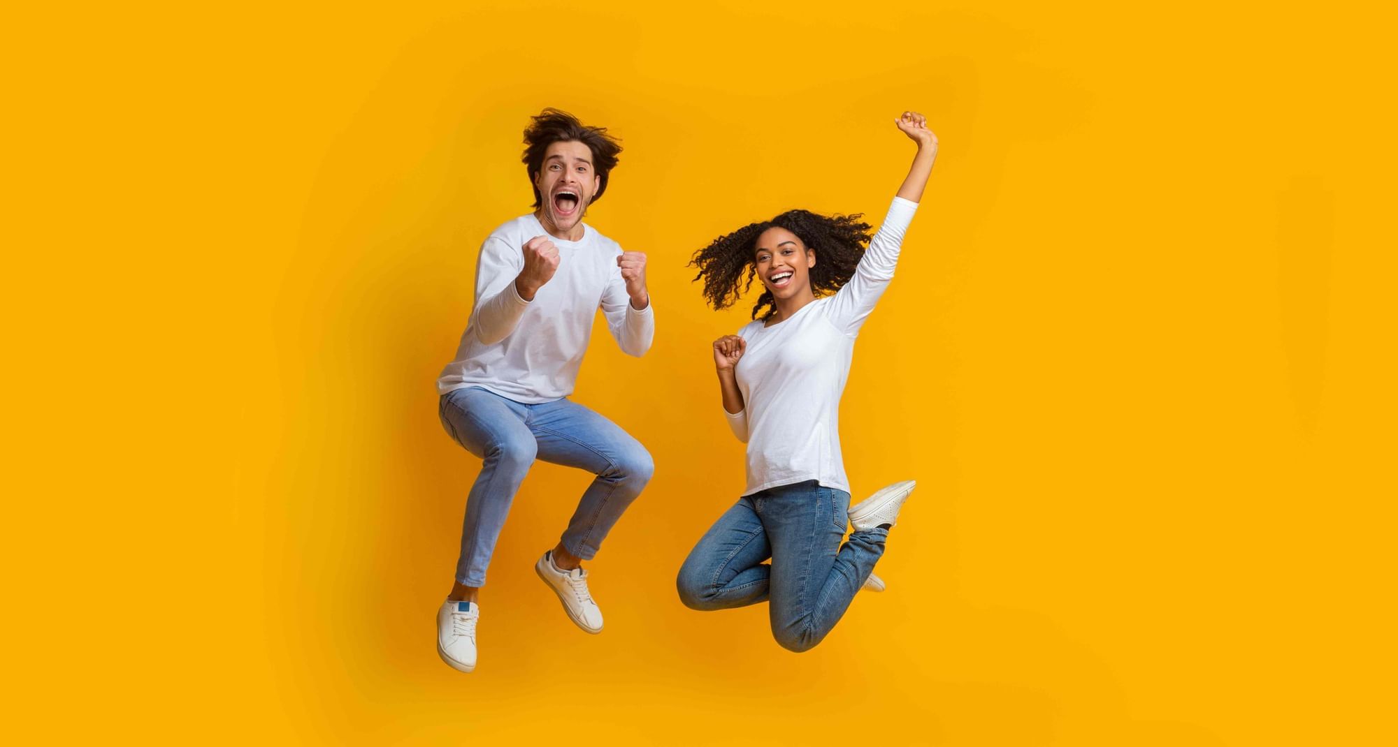 Two people in white shirts jump energetically in a yellow background at Cove Pocono Resorts