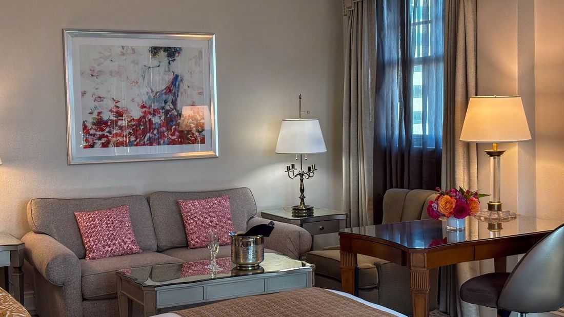 Corner King features Grey sofa by a wooden desk under glowing lamps at Warwick Melrose Dallas