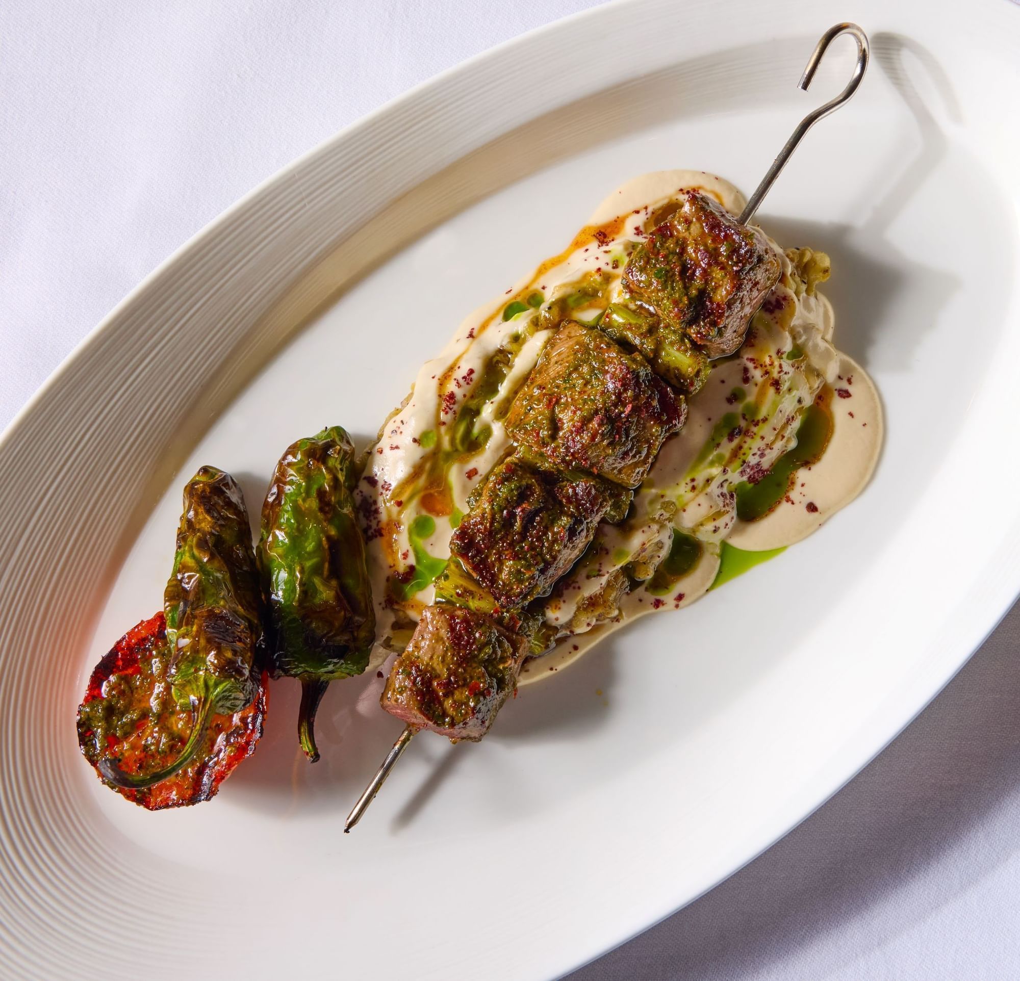A savory meat skewer with roasted vegetables and a creamy sauce in Whitcomb's Terrace at The Londoner Hotel