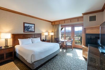 Bedroom at Lake Placid Club Grandview features a king-size bed and French doors leading to a balcony with mountain views