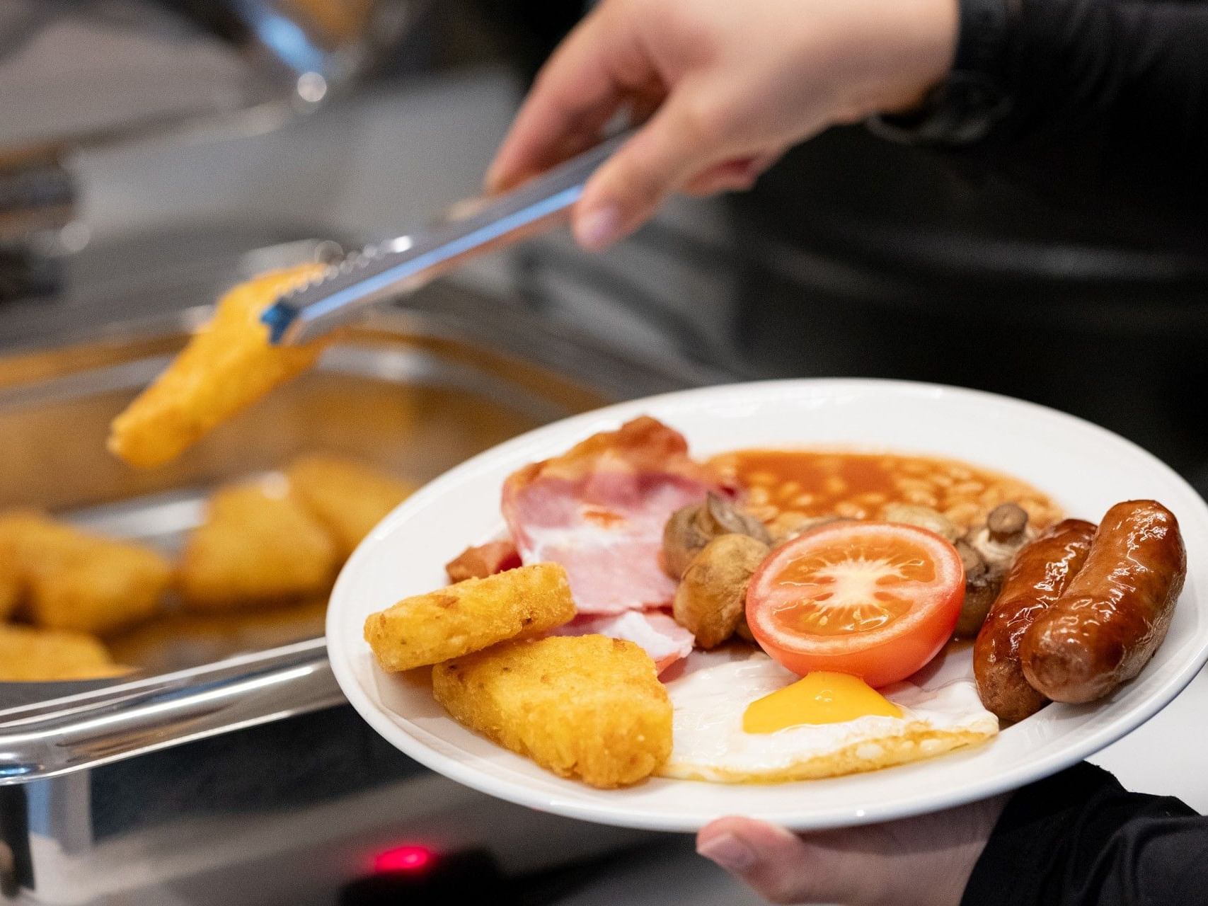 Hand serving a hash brown onto an English breakfast plate at Sandman Sheffield Quays, one of the top hotels in Sheffield