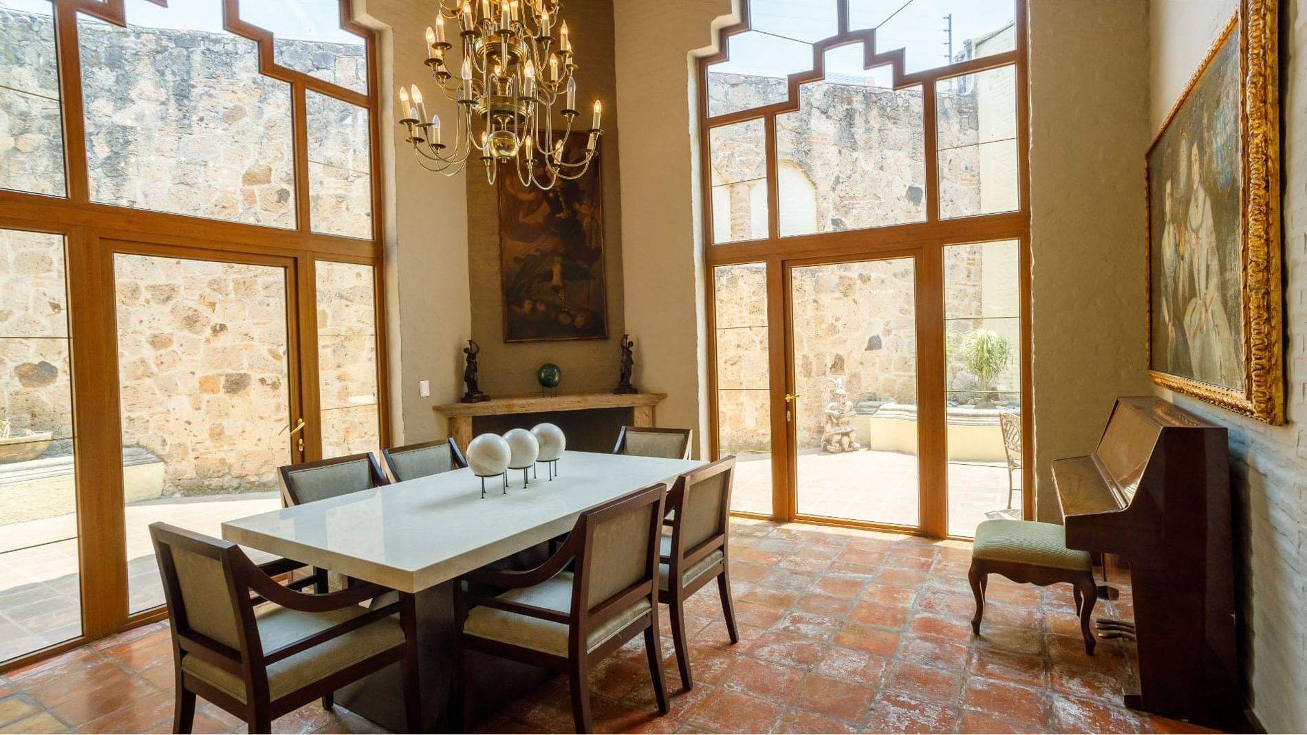 King Presidential Suite with terracotta floors and a piano by tall glass windows at Quinta Real Guadalajara