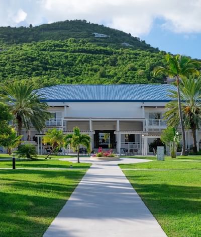 Vue extérieure de l'hôtel Saint Martin Beach avec des pelouses vertes, entouré de collines verdoyantes