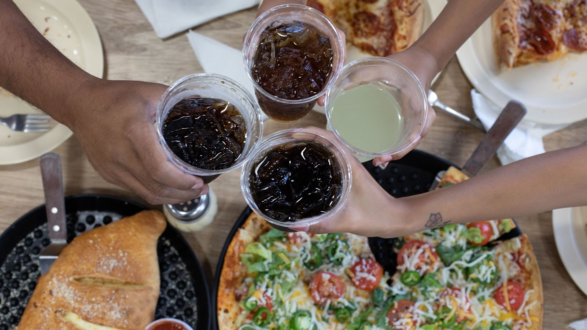 Close-up view of four people cheering with dinks in Bruno’s Pizzas at Watersound Inn