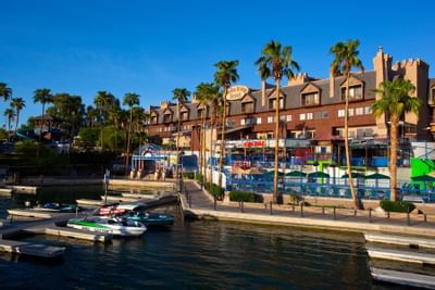 Waterfront view of resort building with palm trees, marina with boats, and colorful water slides at London Bridge Resort