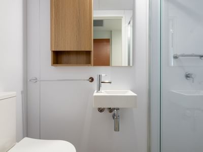 Modern bathroom with toilet, sink, and glass shower at UniLodge Brisbane City.