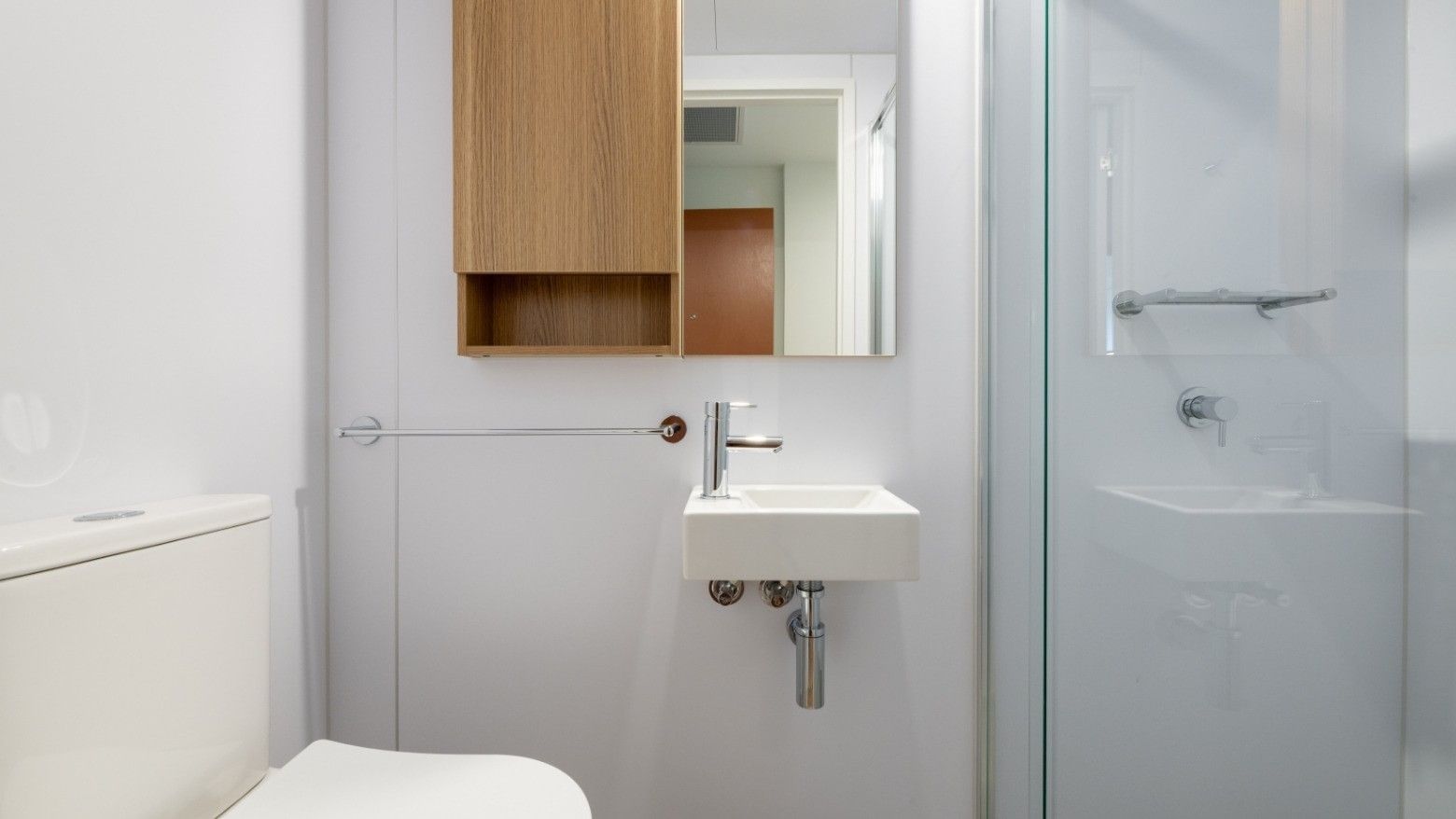 Modern bathroom with toilet, sink, and glass shower at UniLodge Brisbane City.