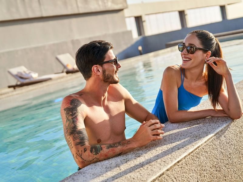 Couple lounging in the outdoor pool at IOH Freestyle Hotels