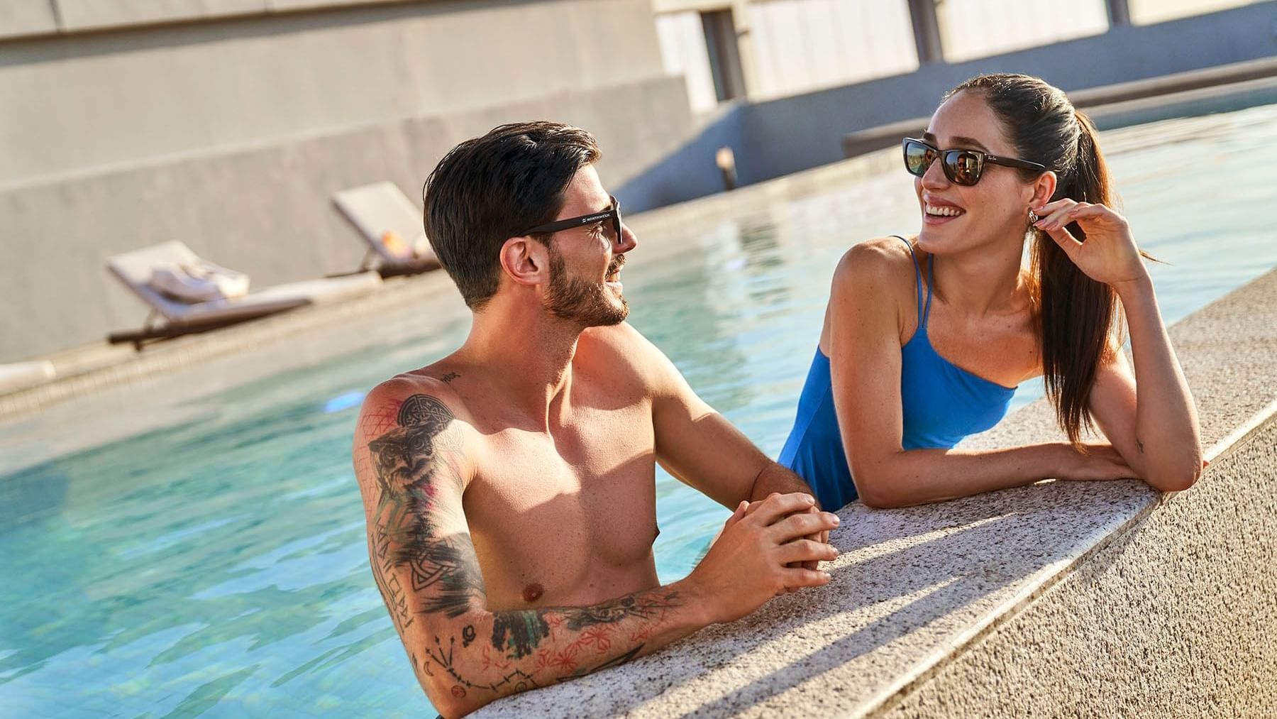 Couple lounging in the outdoor pool at IOH Freestyle Hotels