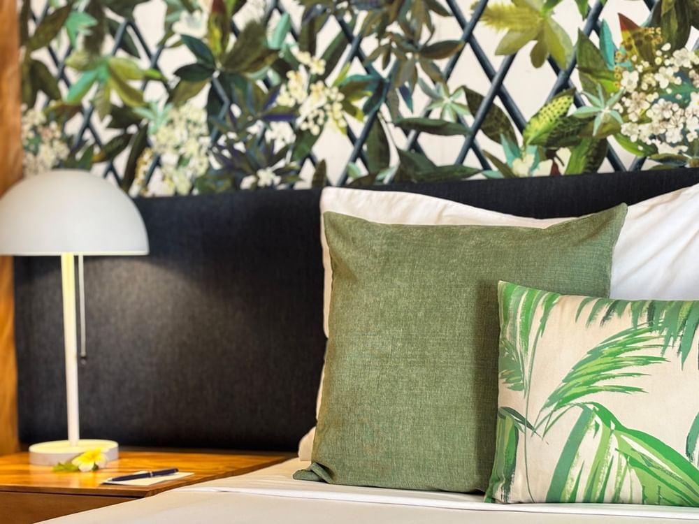 Lagoon Superior Room bed with green pillows and a nightstand lamp at Warwick Le Lagon - Vanuatu, Efate.