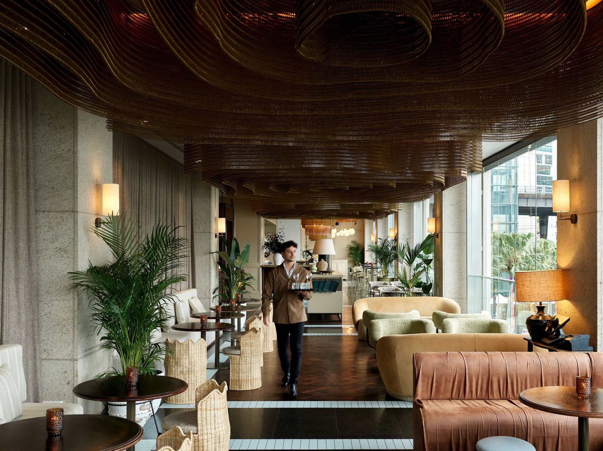Waiter approaching the dining and lounge area with a tray of drinks served at Pullman Quay Grand Sydney