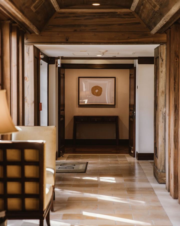 Wooden corridor leading toward framed artwork above dark console table in elegant hallway inside The Brazilian Court