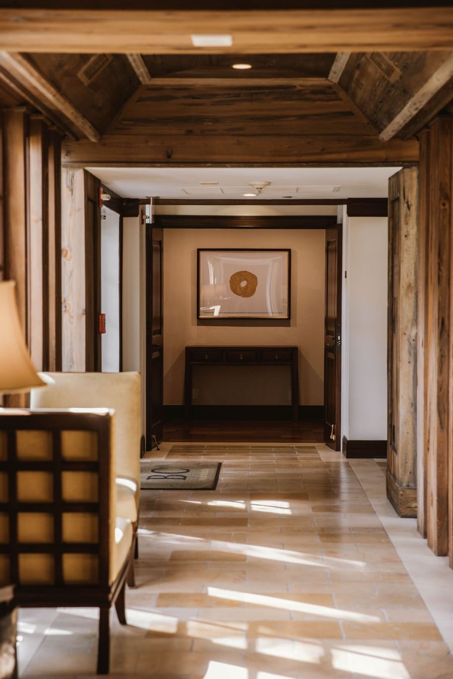Wooden corridor leading toward framed artwork above dark console table in elegant hallway inside The Brazilian Court