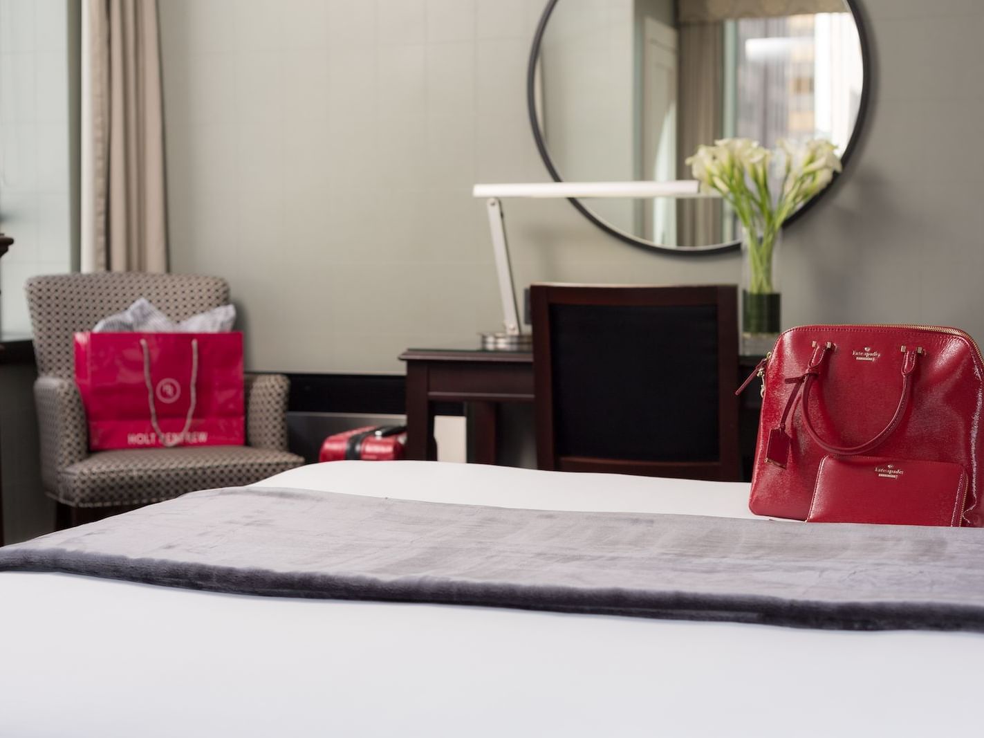 red bag on queen bed facing circular mirror