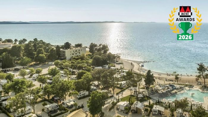 Aerial view of a Falkensteiner Camping Zadar with RVs, trees, and a beach, with ACSI Awards 2026 logo.