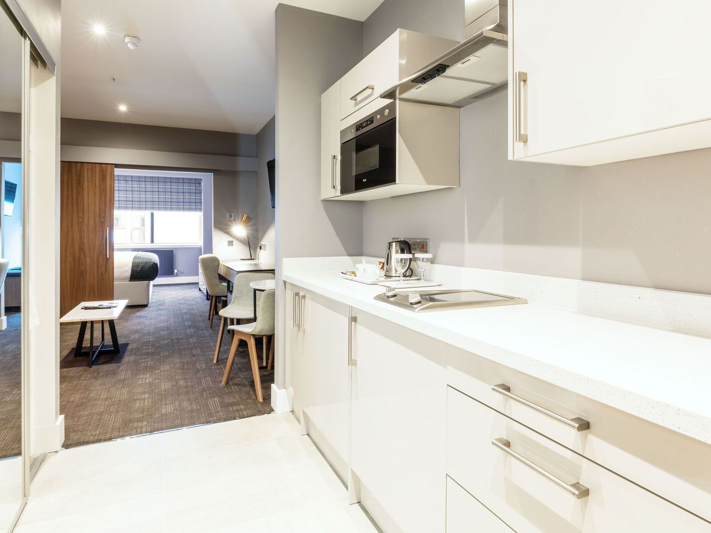 The Pantry with White Pantry Cupboards and with Kitchen Supplies and White Furniture in the Corporate King Suite at Sandman Signature Aberdeen Hotel