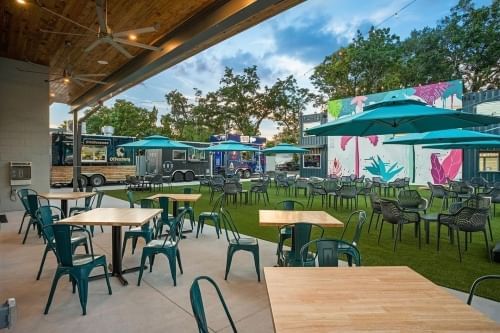 tables and chairs spread throughout an indoor/outdoor beer garden surrounded by food trucks. À la Cart is a great destination for a romantic date in Orlando.