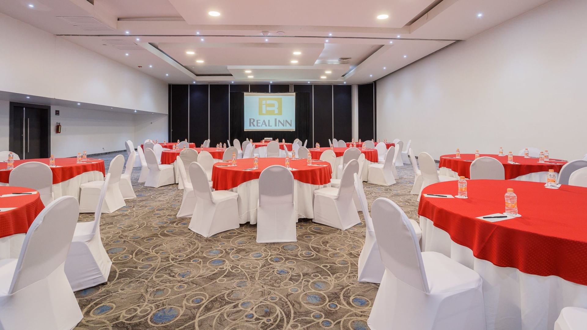 Salón Palermo en Real Inn Tijuana, Tijuana, con mesas redondas y sillas cubiertas de blanco.