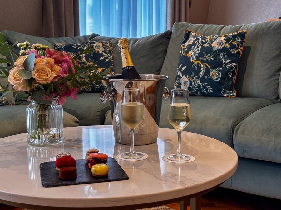 Living room scene with a vase of flowers, champagne, two filled flutes, & macarons at Warwick Reine Astrid - Lyon