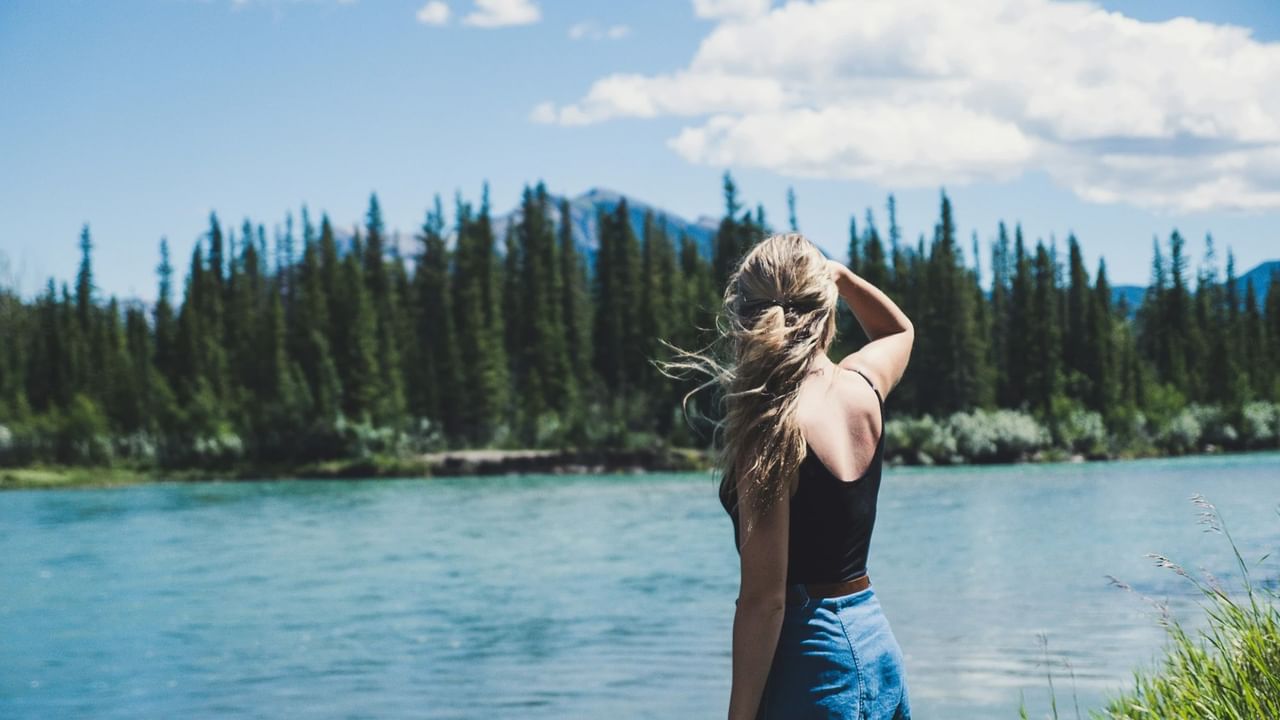 A person on an easy hike in Canmore admires the view on a sunny day.