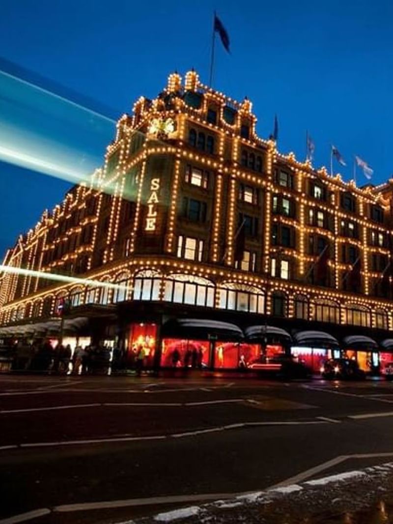 Exterior of Harrods illuminated by golden lights at night near The Capital Hotel, Apartments and Townhouse