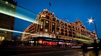 Exterior of Harrods illuminated by golden lights at night near The Capital Hotel, Apartments and Townhouse