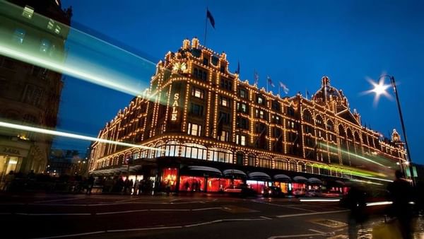 Exterior of Harrods illuminated by golden lights at night near The Capital Hotel, Apartments and Townhouse