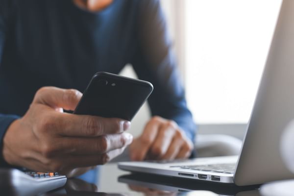 Man texting while on laptop