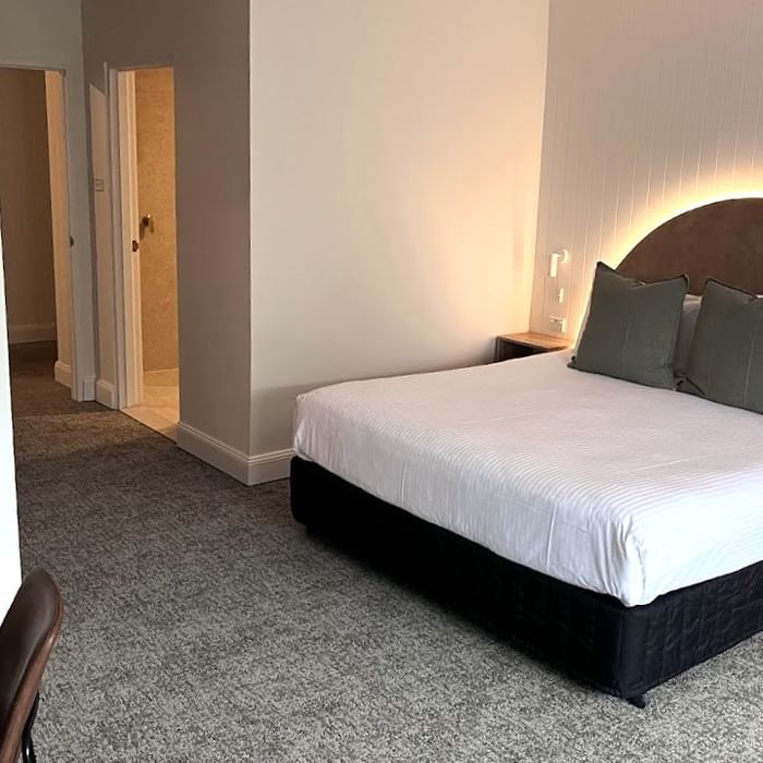 Modern hotel room with white bedding and gray carpet at Mercure Charlestown.