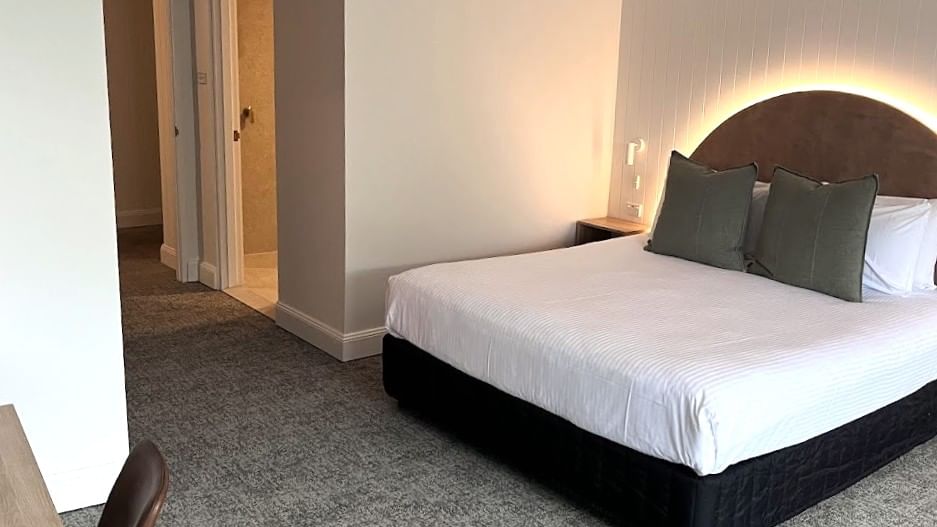 Modern hotel room with white bedding and gray carpet at Mercure Charlestown.