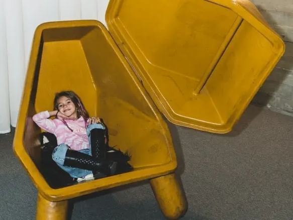 Bambina che sorride e si siede in una struttura gialla aperta a DUPARC Contemporary Suites