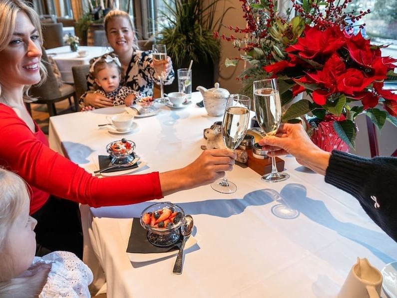 Three adults toasting with champagne flutes at a white-clothed table decorated with poinsettias at Spring Creek Resorts