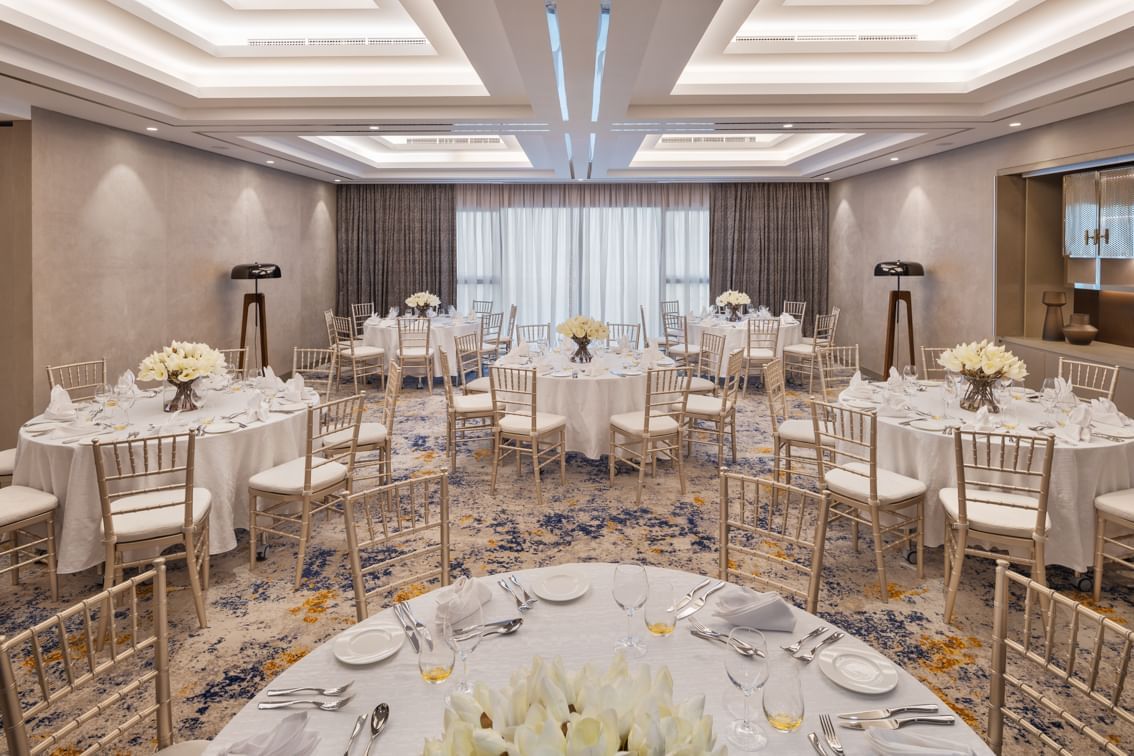 Elegant dining set in Business Studio 3 at Paramount Hotel Midtown with round tables, floral centerpieces, and golden chairs