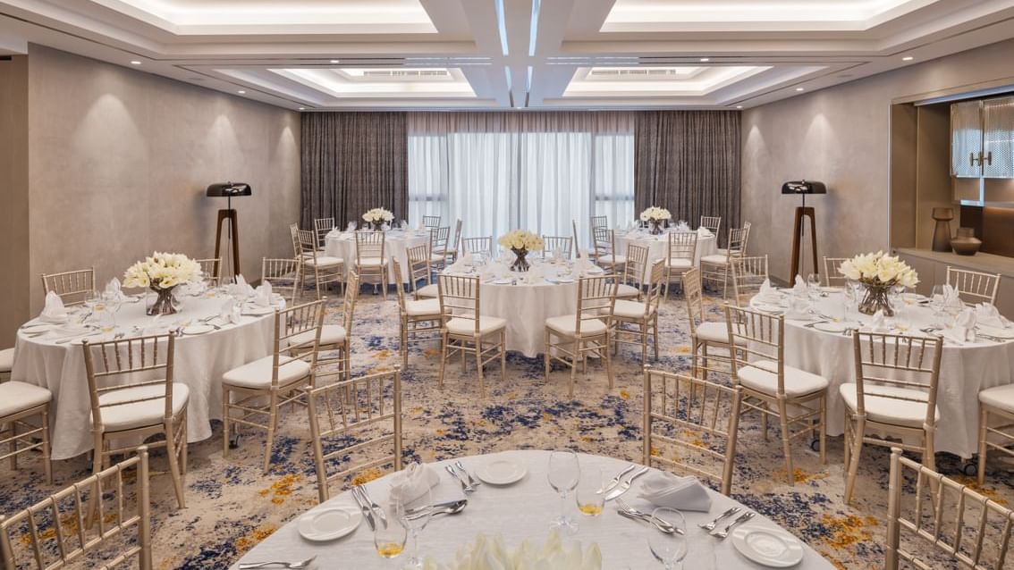 Elegantly set round dining tables with floral centerpieces in Business Studio 1 at Paramount Hotel Midtown