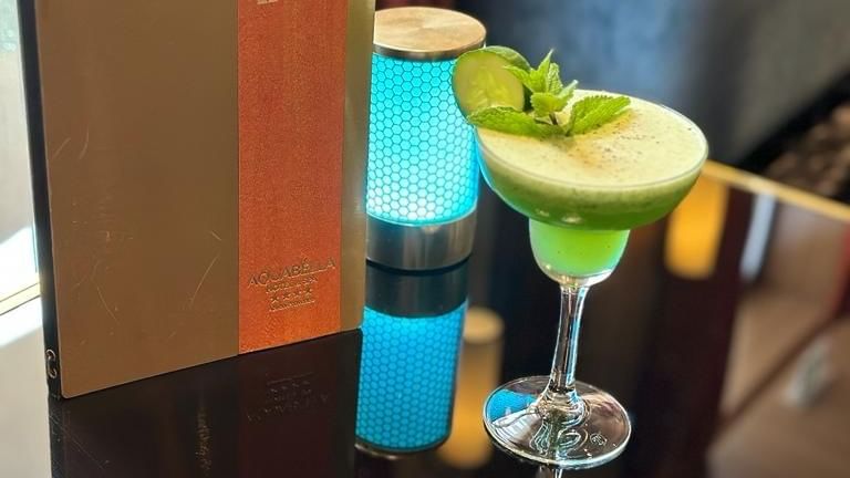 Menu du bar et cocktail vert dans un verre à martini sur une table avec réflecteur.