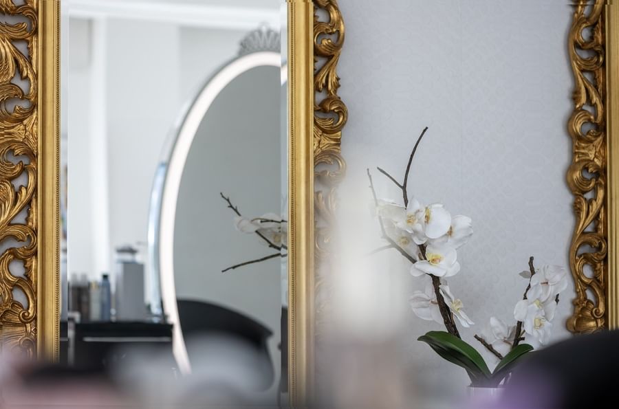 White orchid by a gold-framed mirror under soft light at Warwick Melrose Dallas