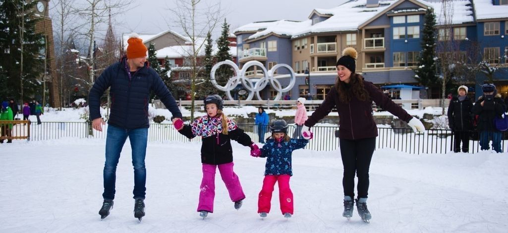 Family ice skating outdoors in Whistler Village during winter near local accommodations