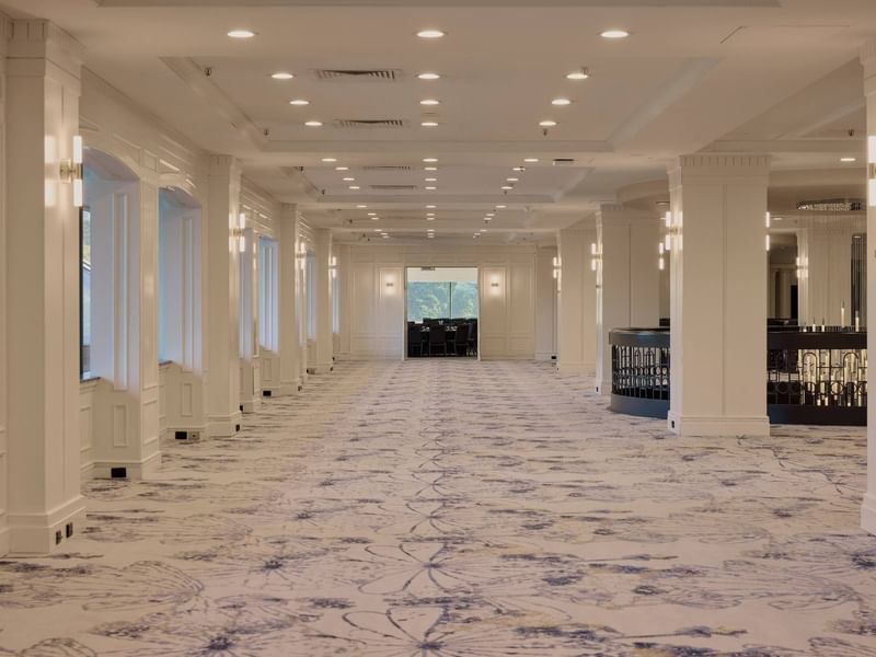 Spacious conference foyer with elegant white columns, patterned carpet, and modern lighting at Pullman East Melbourne
