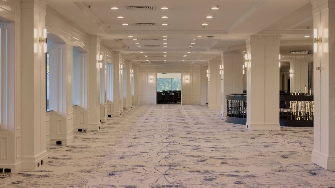 Spacious conference foyer with elegant white columns, patterned carpet, and modern lighting at Pullman East Melbourne
