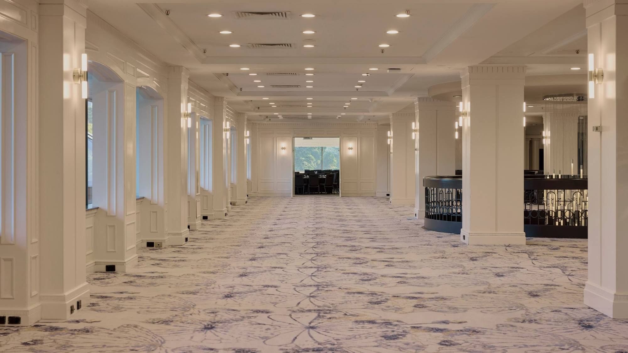 Spacious conference foyer with elegant white columns, patterned carpet, and modern lighting at Pullman East Melbourne