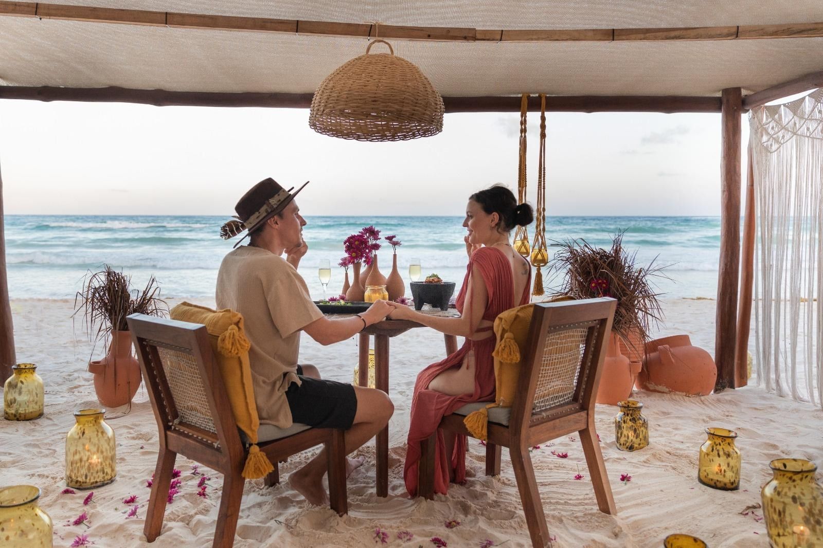 A couple holding hands over a private dinner on La Zebra's beach