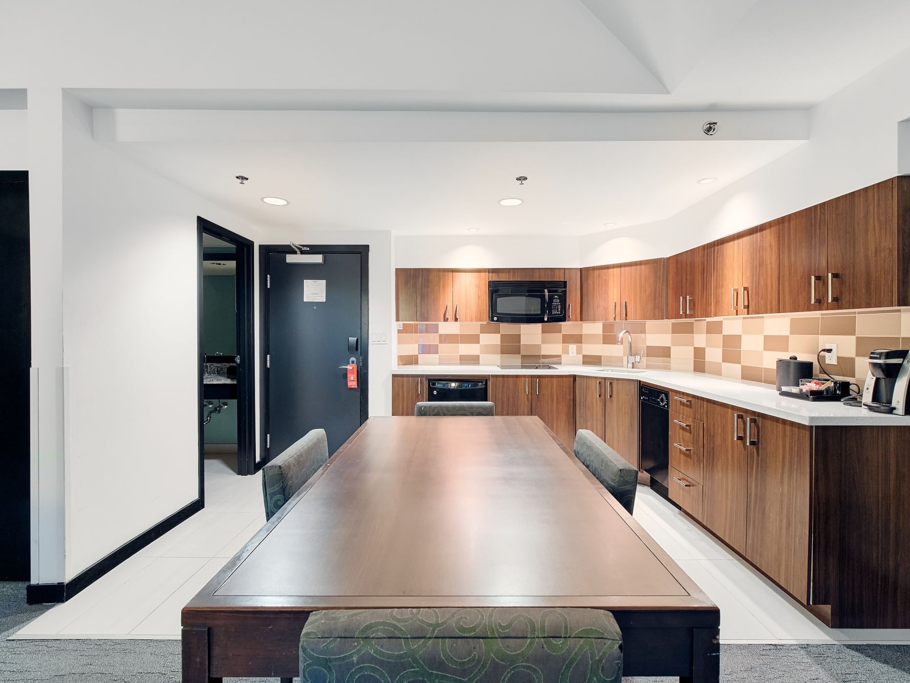 Two Bedroom Suite modern kitchen at the Paradox Aava Whistler hotel with wooden cabinets, and microwave.