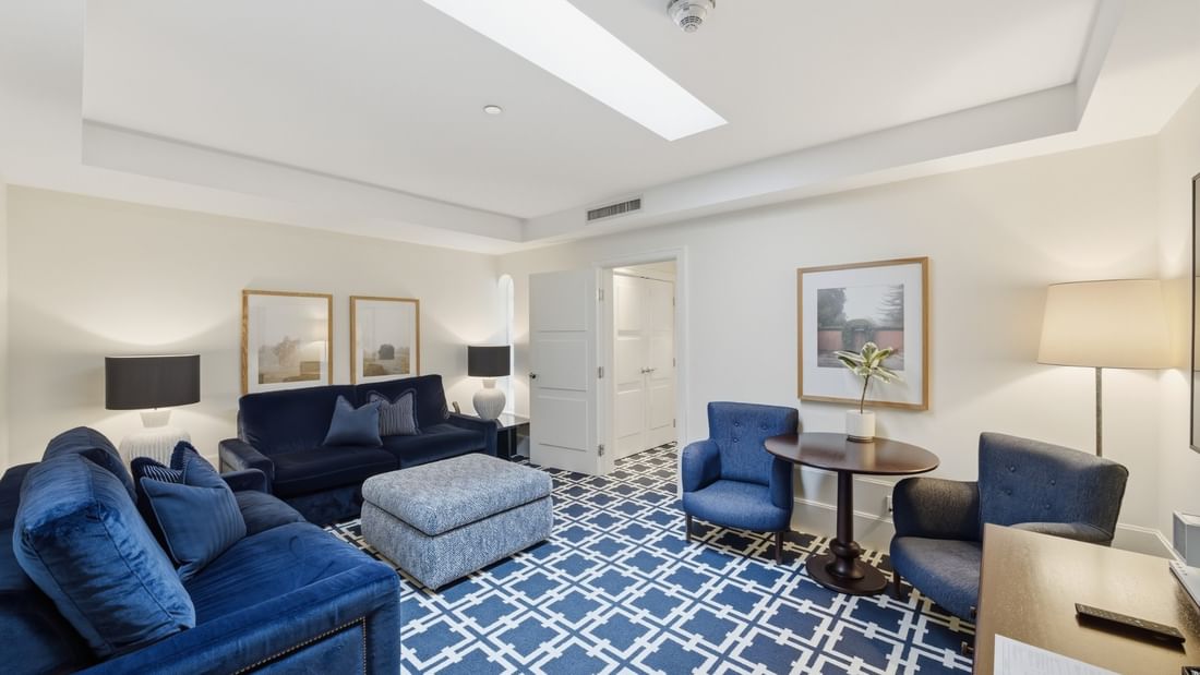 Spacious Deluxe King Suite living area with blue sofas, patterned carpet, and skylight at el PRADO Hotel, Palo Alto.
