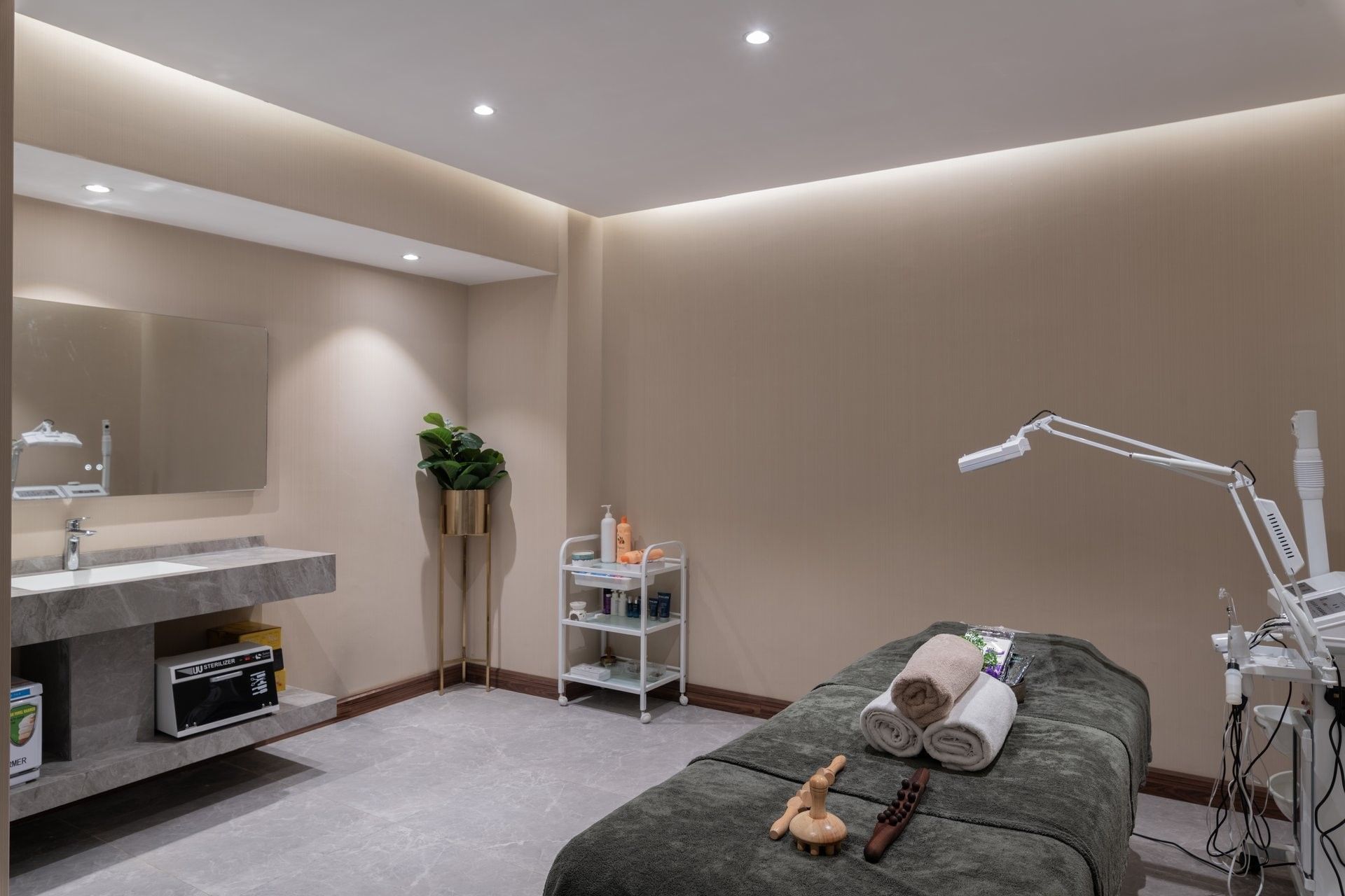 Therapy bed by a utility cart and marble wash station under a plain ceiling in Golden Time Spa at Warwick Al Taif Hotel
