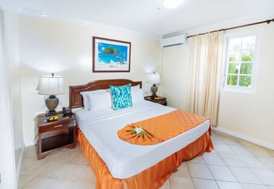 Cozy room featuring a queen bed, a decorative painting, and bedside lamps in One Bedroom Croton Suite at Bay Gardens Hotel