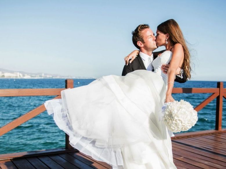 A wedded couple kissing on the pier at Marbella Club Hotel